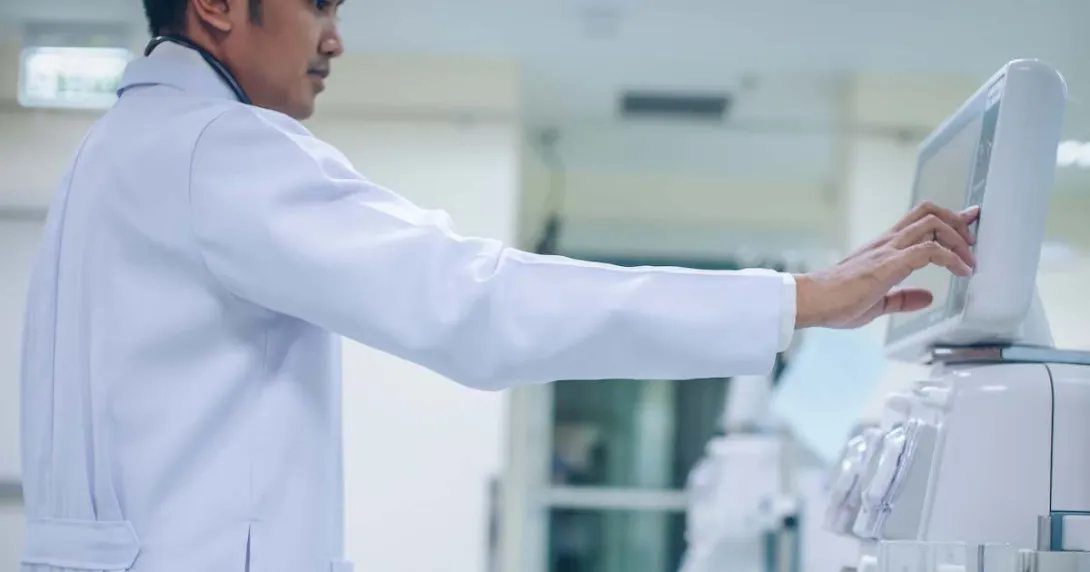   Doctor looking at a dialysis machine while in a care clinic or hospital