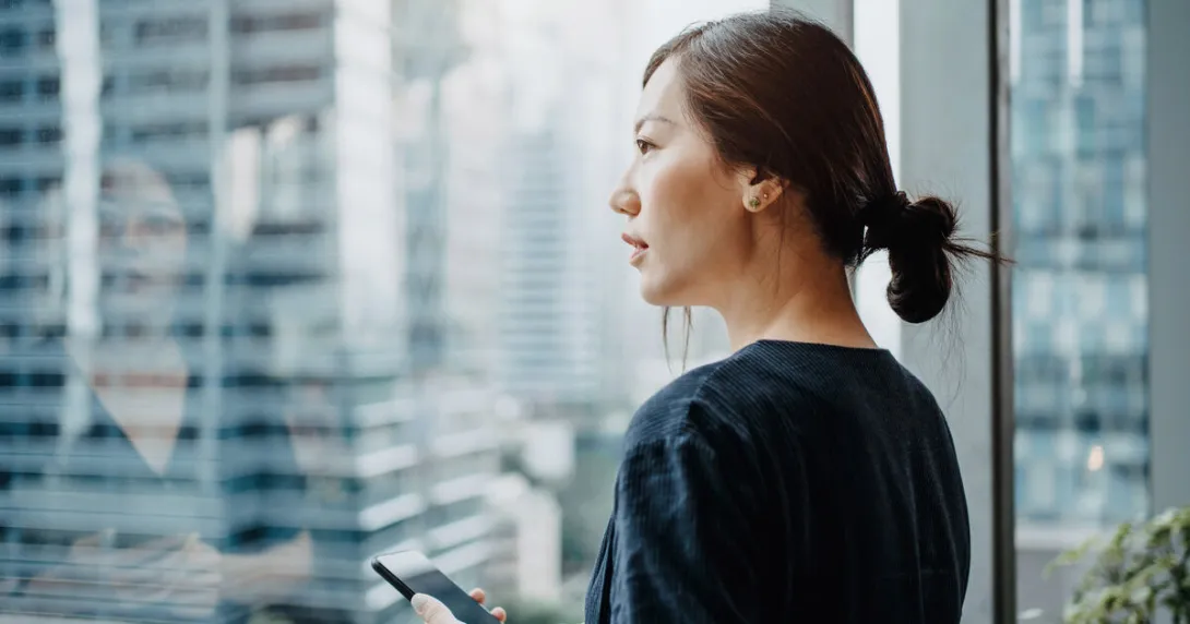 A person holding a phone looking out the window